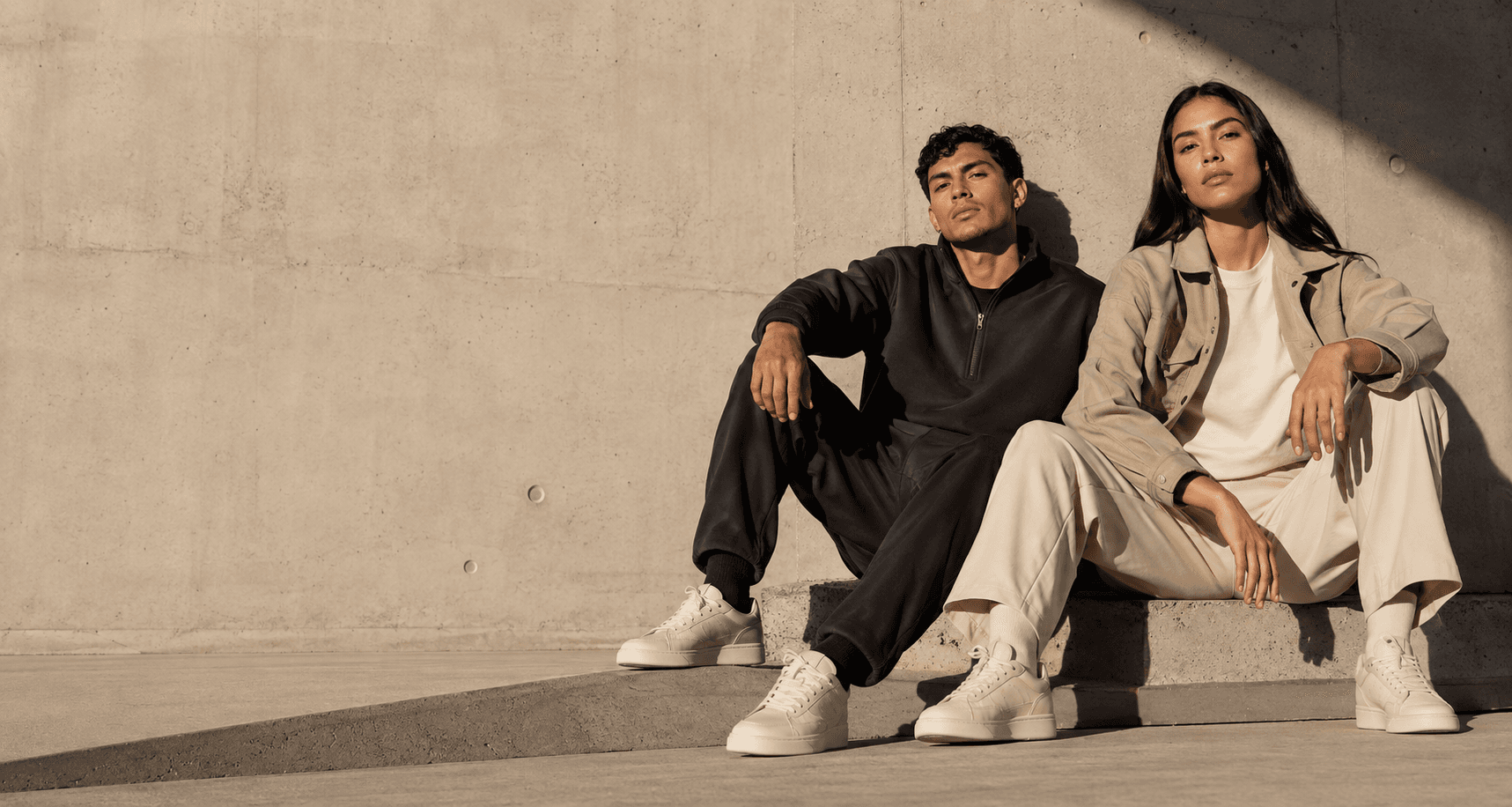 Dos modelos con ropa urbana neutra y sneakers